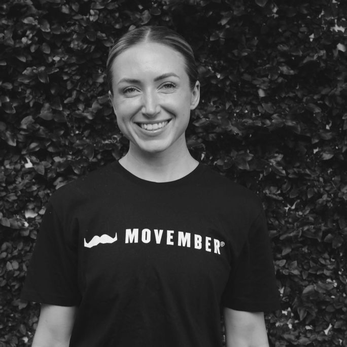 Photo of athletic woman wearing a Movember-branded shirt, smiling to camera.